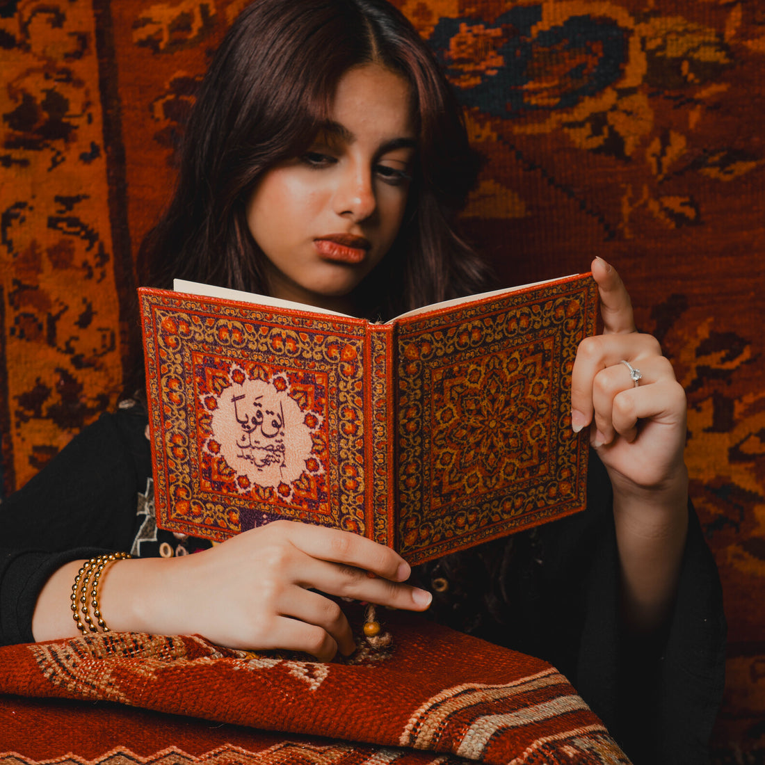 Woman reading a decorated book in a warm-toned room.